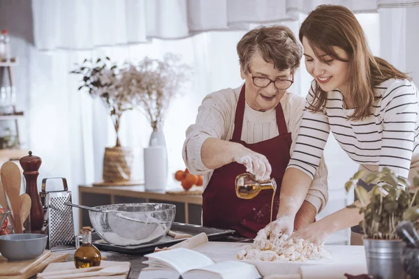 Mormor att lägga till olja i degen — Stockfoto