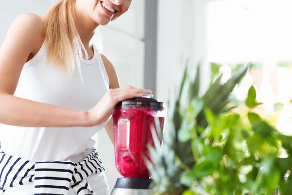 Sorrindo mulher misturando smoothie vermelho — Fotografia de Stock