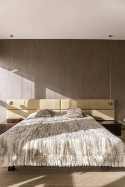 Двуспальная кровать с бежевым покрывалом — стоковое фото
