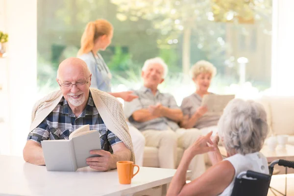 Sorridente libro di lettura uomo anziano — Foto Stock