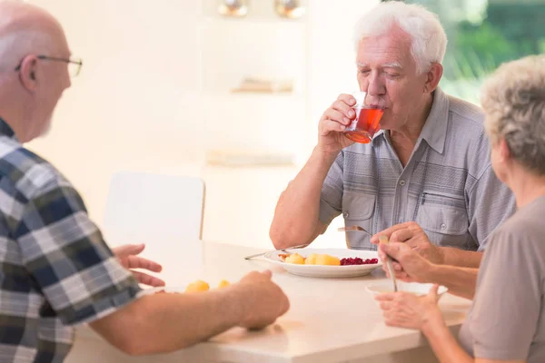Пожилой человек пьет сок — стоковое фото