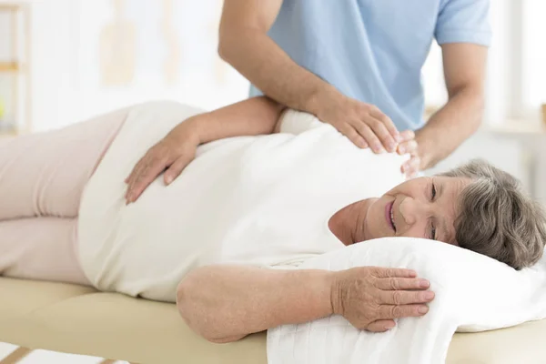 Massaggiatore massaggiando le spalle della donna anziana — Foto Stock