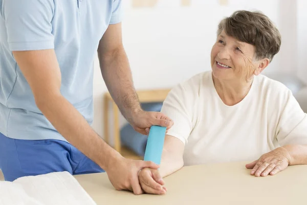 Physiotherapist putting kinesiotape on arm — Stock Photo, Image