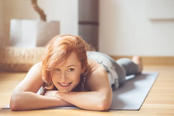 Mujer sonriente en esterilla de yoga —  Fotos de Stock