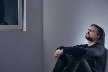Duvara oturan üzgün adam