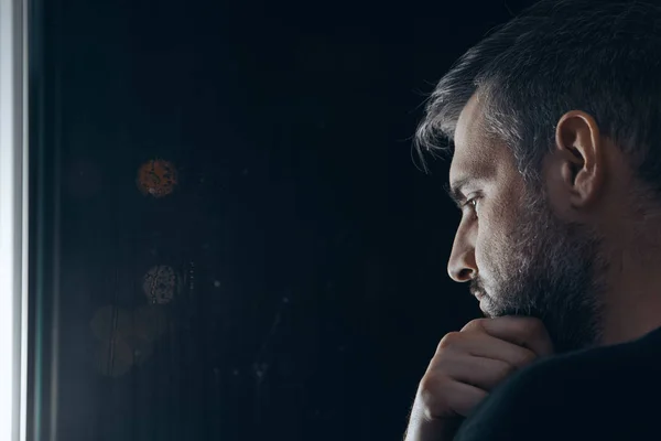 Man holding chin beside window — Stock Photo, Image