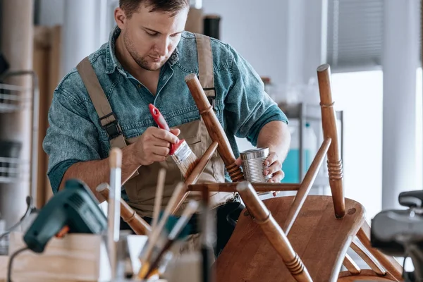 Плотник рисует деревянный стул — стоковое фото