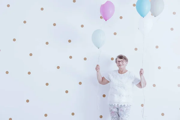 Улыбающаяся бабушка с разноцветными воздушными шарами — стоковое фото