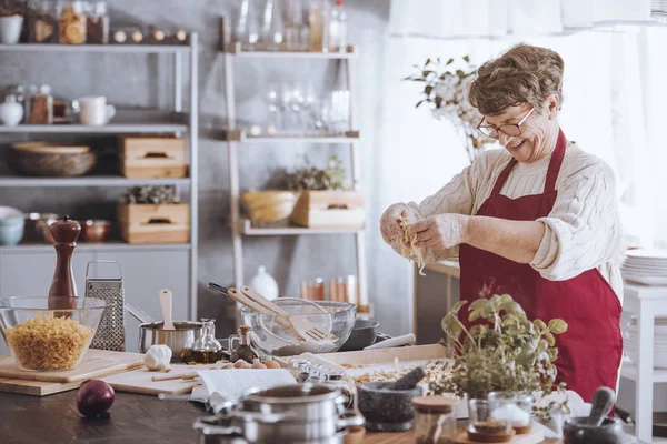 Grand-mère ajoutant oeuf à la farine — Photo