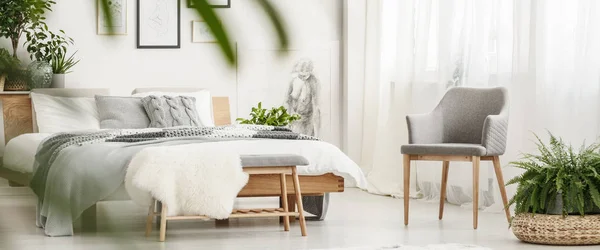 Grey chair in bright bedroom — Stock Photo, Image