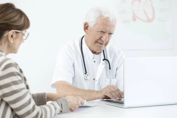 Médico usando laptop durante a consulta — Fotografia de Stock