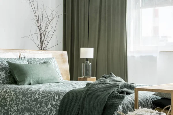 Зеленое одеяло на двуспальной кровати — стоковое фото