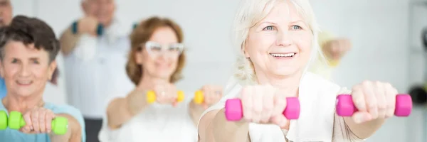 Senior woman lifting pink dumbbells — Stock Photo, Image