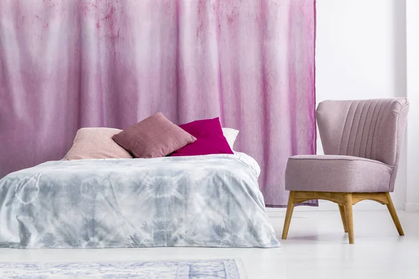 Poltrona rosa ao lado da cama — Fotografia de Stock