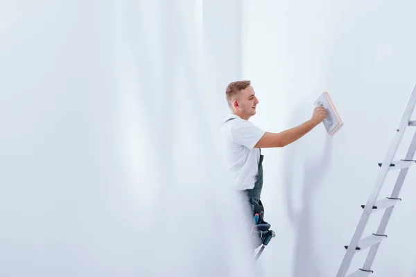Handyman cleaning white wall — Stock Photo, Image