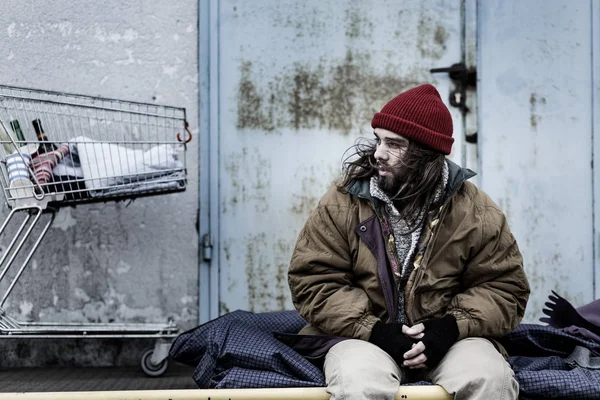 Dirty beggar sitting on night-bag — Stock Photo, Image