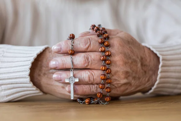 Mani di anziano con rosario rosso — Foto Stock