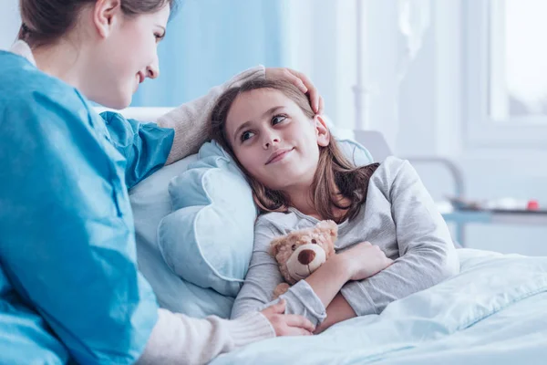 Lächelnde Betreuerin besucht krankes Kind — Stockfoto