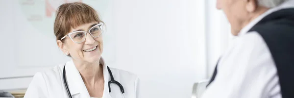 Starší lékař, usmívají se na pacienta — Stock fotografie