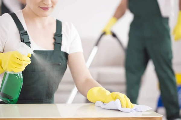 Putzfrau sprüht Tisch — Stockfoto