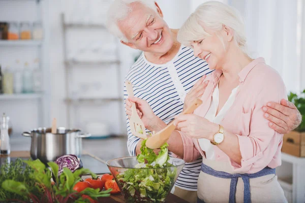 Happy grandmother mixing salad — Stock Photo, Image