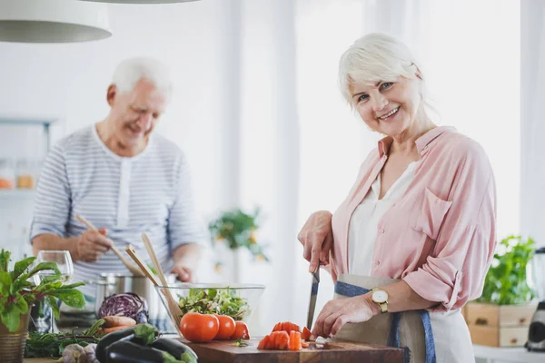 Lächelnde Seniorin schneidet Tomaten — Stockfoto