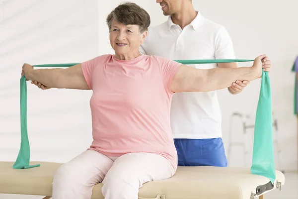 Bejaarde vrouw uitrekken tijdens fysiotherapie — Stockfoto