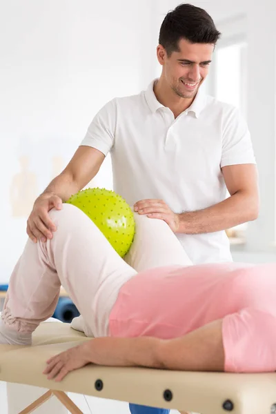 Patient squeezing ball between knees — Stock Photo, Image