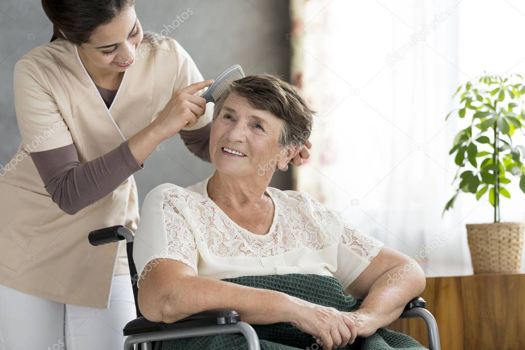 Volunteer combing older patient's hair