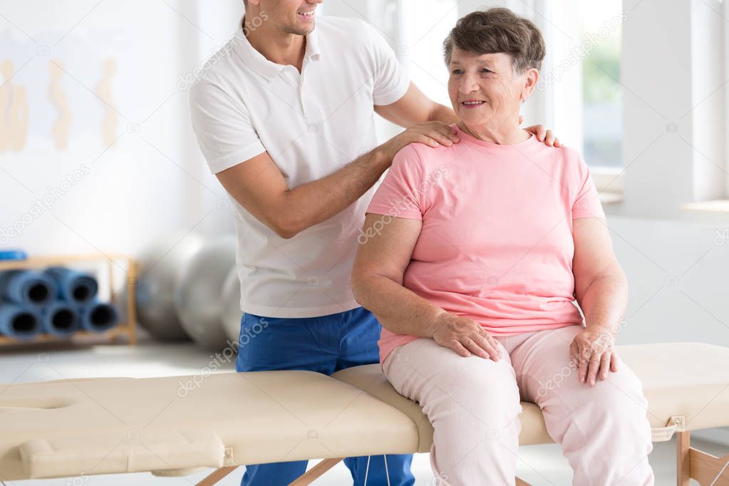 Physiotherapist massaging smiling senior woman