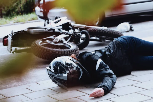 Female motorcyclist lying unconscious — Stock Photo, Image