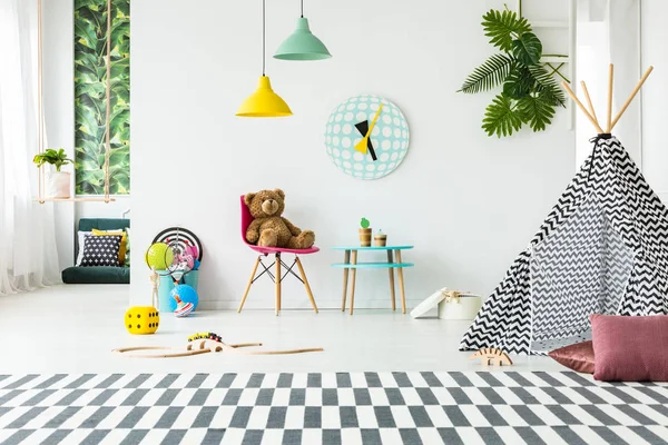 A menina está jogando na sala de jogos infantil berçário escandinavo  brinquedos de madeira e decoração