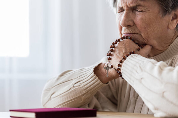 Catholic elderly woman in melancholy