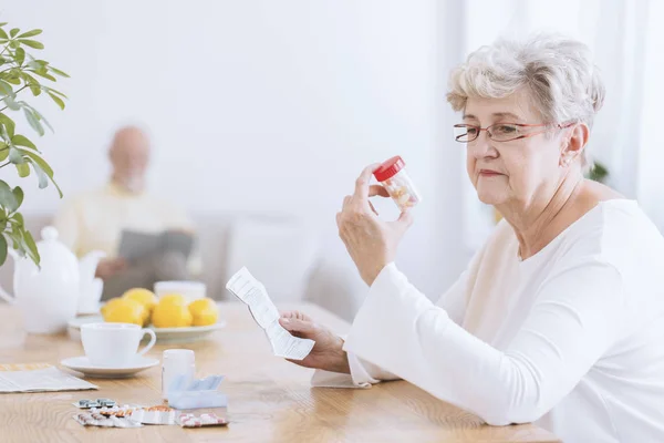 Грустная пожилая женщина с таблетками — стоковое фото