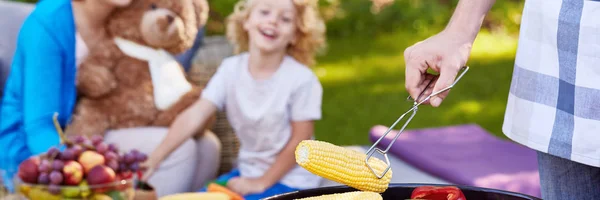 Чоловік готує кукурудзу на грилі для хлопчика — стокове фото