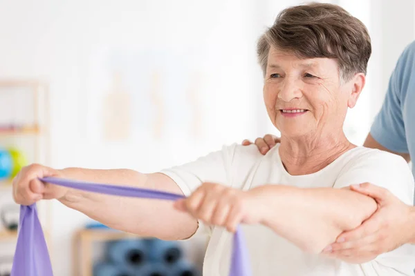 Mujer anciana tirando de la banda elástica — Foto de Stock