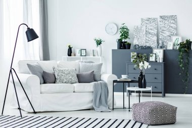 Nordic aydınlık oturma odası iç beyaz kanepe, taze bitki ve siyah metal lamba ile