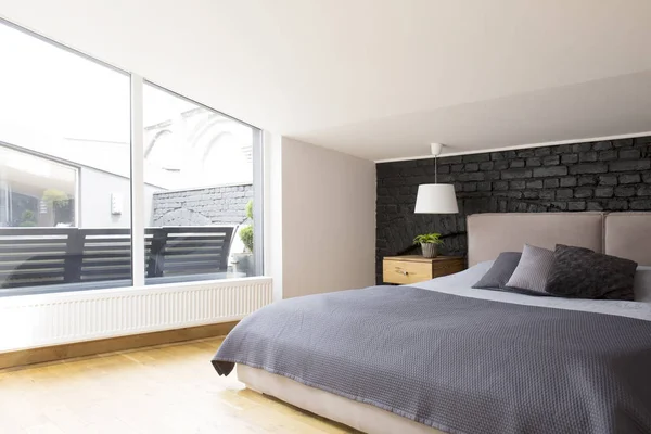 宽敞卧室内的窗户与黑色砖墙床上的灰色床上用品 — 图库照片