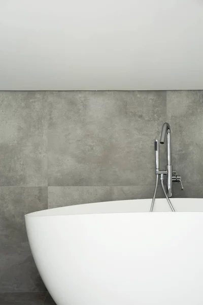 屋根裏部屋の簡単な浴室内部のグレーの壁に白のバスタブ — ストック写真