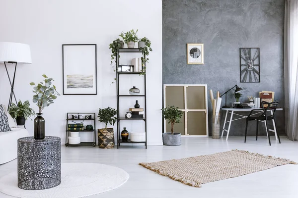 Modern office space interior with plants, metal table, beige rug and grey wall