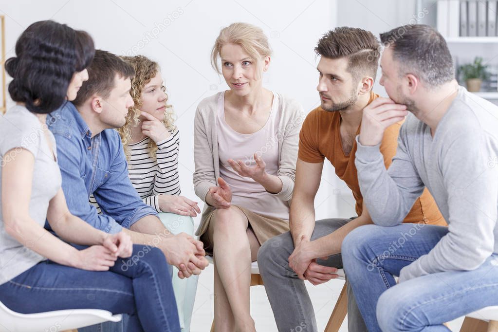 Female psychologist explaining the process of healing to a group of people fighting depression