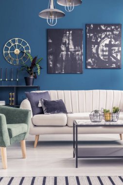 Altın yuvarlak saat ve mavi siyah resim sergisi salon iç kanepe lambalar altında ile duvar