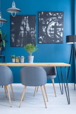 Mavi duvar siyah boya ile yemek odası iç ahşap masa üzerinde bitki