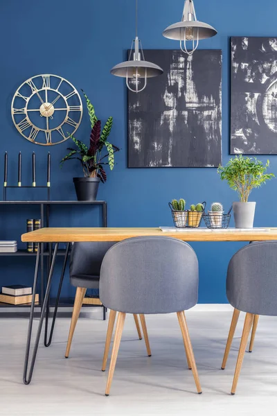 蓝色餐厅的木桌上有仙人掌的灰色椅子 金色的钟和黑色的画 — 图库照片