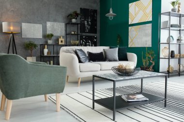 Koltuk, kanepe ve modern resim sergisi ile iç oturma odası eritli halı üzerinde mermer masa üstü duran siyah, metal, endüstriyel tabloyla