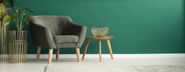 一个舒适的 黑暗的扶手椅和一张木茶几在豪华的 绿色的客厅内 金色的装饰品特写 — 图库照片