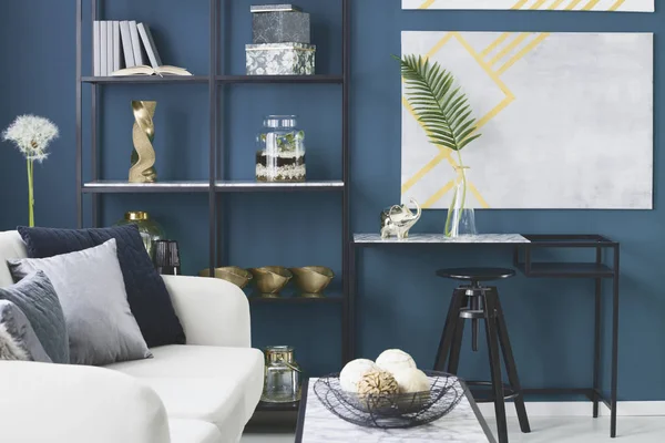 金象和一个玻璃花瓶里的叶子放在蓝色起居室内的大理石桌上 装饰在金属架子上 — 图库照片