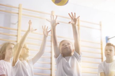 Low angle of active children playing volleyball during physical education classes clipart