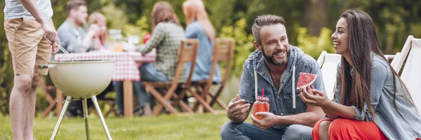 Leende Kvinna Äta Vattenmelon Och Hennes Vän Dricka Juice Trädgårdsfest — Stockfoto