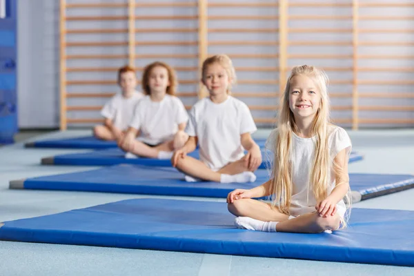 Lachende Meisje Zit Een Blauwe Mat Tijdens Gymnastiek Lessen — Stockfoto